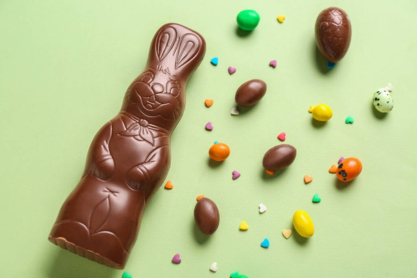 Yeşil arka planda yumurta ve çikolata parçacıkları olan Paskalya tavşanı. - Fotoğraf, Görsel