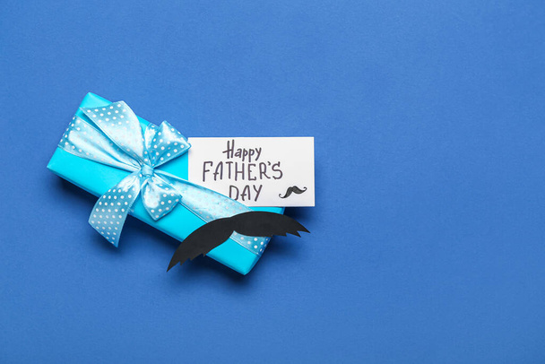 Pudełko na prezenty, papierowe wąsy i kartka z tekstem DZIEŃ HAPPY FATHER 'S na tle koloru - Zdjęcie, obraz