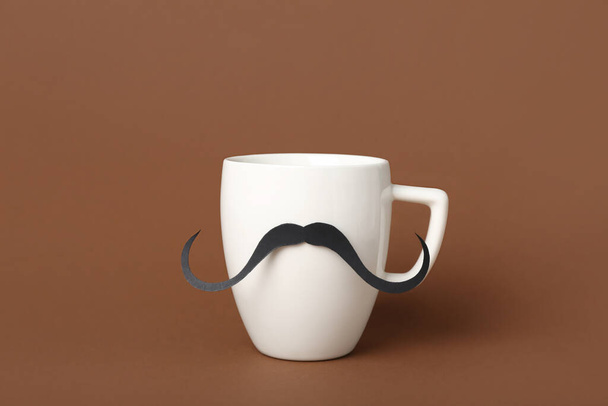 Cup with paper mustache on color background. Father's Day celebration - Φωτογραφία, εικόνα