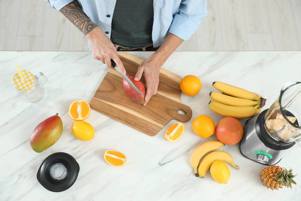 Man preparing ingredients for tasty smoothie at white marble table in kitchen, above view - Photo, Image