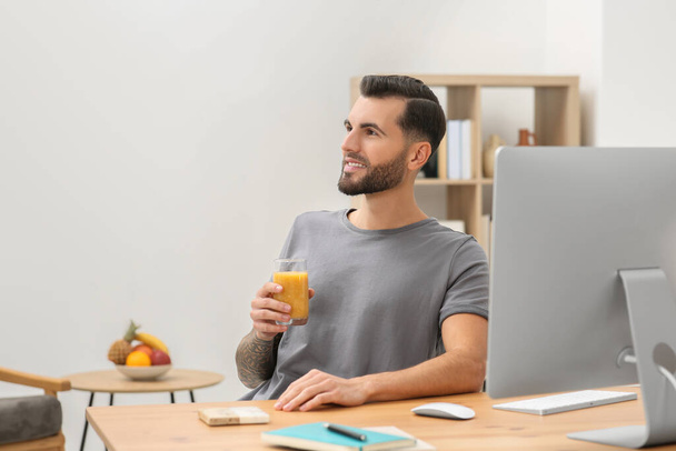 Handsome man with delicious smoothie at workplace in office. Space for text - Fotografie, Obrázek