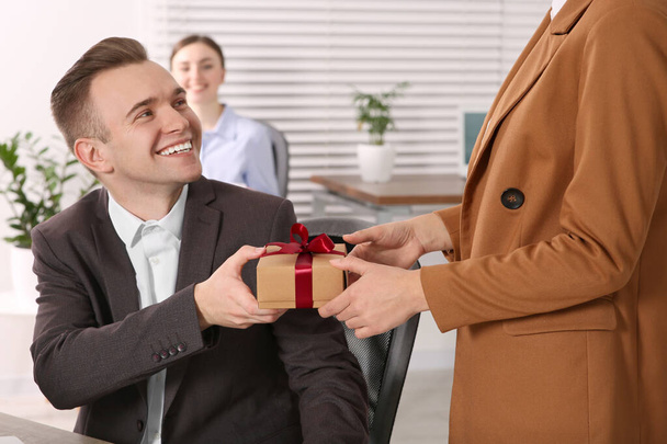 Kobieta prezentuje prezent dla swojego kolegi w biurze - Zdjęcie, obraz