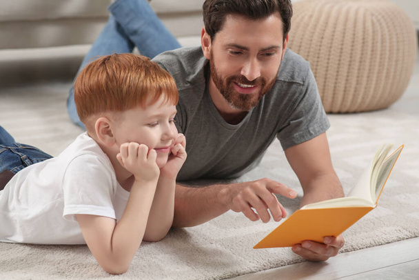 Father reading book with his child on floor at home - Foto, Imagen
