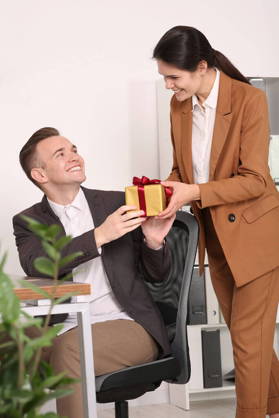 Woman presenting gift to her colleague in office - Foto, Bild