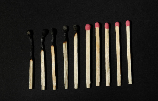 Burnt and whole matches on black background, flat lay. Stop destruction concept - Фото, зображення