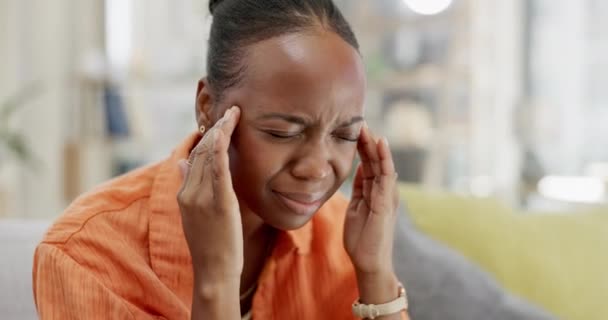 Kranke, massierte und schwarze Frau mit Kopfschmerzen, Stress oder Schwindel zu Hause. Angst, trauriges und afrikanisches Mädchen massiert ihre Schläfen gegen Migräne, Müdigkeit und psychische Probleme auf dem Sofa. - Filmmaterial, Video