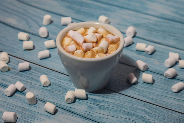 Close up of Cup hot chocolate marshmallows cacao. Cozy Coffee with marshmallows on wooden blue background. Copy space for text. Wallpaper design. Sweet unhealthy food  - Foto, afbeelding