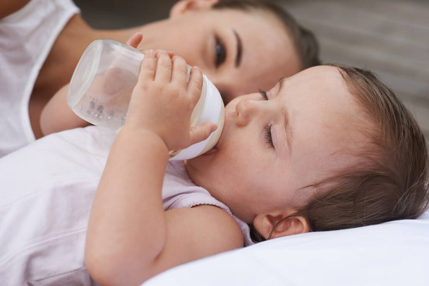 Keeping baby healthy. A mother looking on lovingly as her baby drinks from a bottle - Foto, imagen