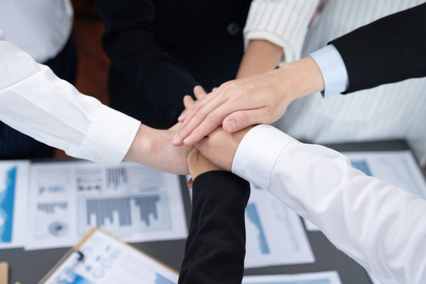 Top view closeup business team of suit-clad businesspeople join hand stack together. Colleague collaborate and work together to promote harmony and teamwork concept in office workplace. - Foto, Imagen