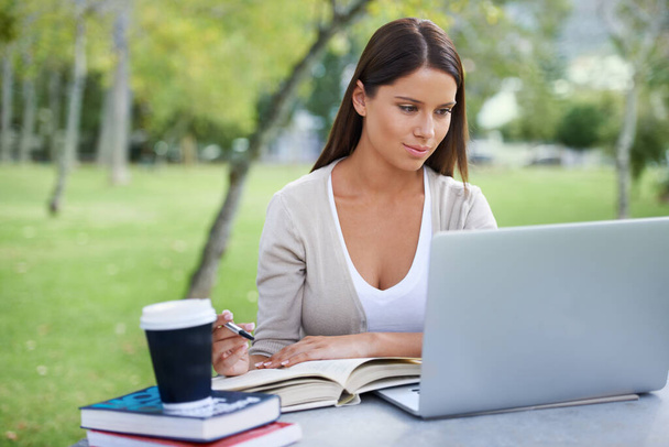 Свіже повітря змушує мене йти. Молода жінка сидить у парку, працюючи на ноутбуці з чашкою кави поруч з нею
 - Фото, зображення