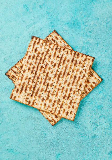 ペサハのお祝いの概念-ユダヤ人の休日ペサハ。Matzahの正方形は、青い背景の上に1つを積み上げました。平敷. - 写真・画像