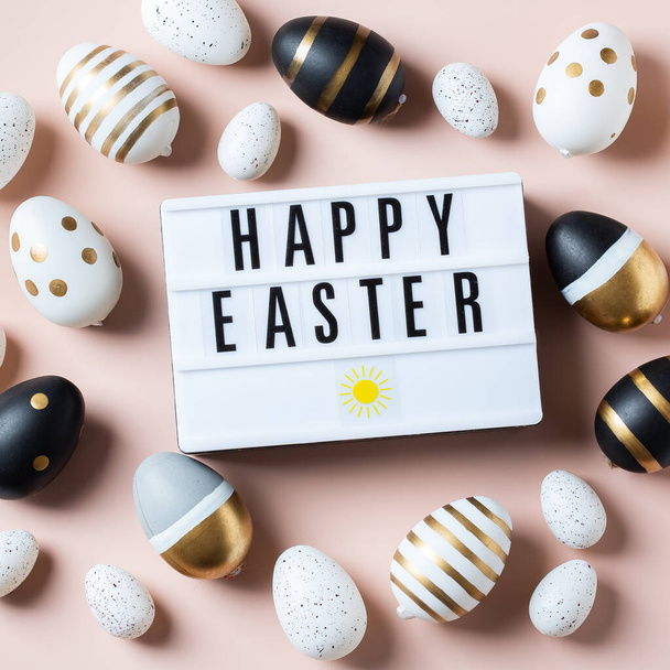 Pembe arka planda altın, beyaz, siyah noktalı ve çizgili yumurtalarla mutlu Paskalya çerçeveleri. Üst manzara, düz yatış. Modern Paskalya tebrik kartı - Fotoğraf, Görsel