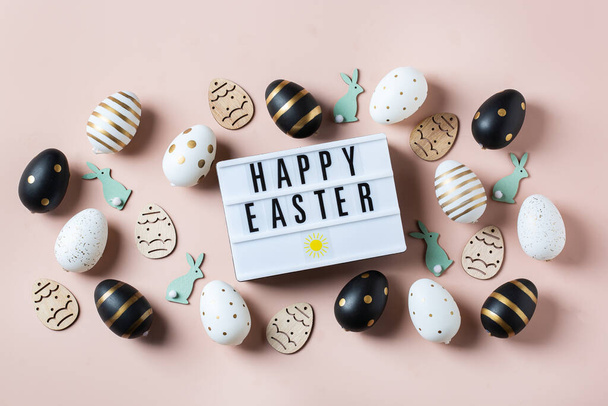 Happy Easter frame with golden, white, black dotted and striped eggs on a pink background. Top view, flat lay. Modern Easter greeting card - Valokuva, kuva