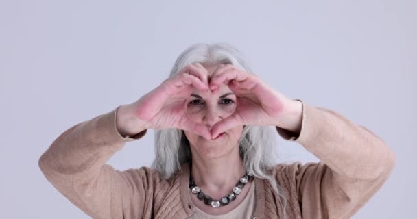 Anciana mujer de pelo gris mostrando gesto en forma de corazón con las manos 4k película cámara lenta. No olvides el concepto de padres - Metraje, vídeo