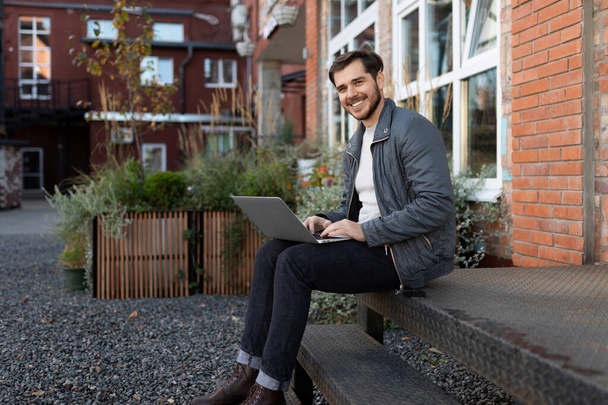 europejski freelancer broadcasting siedząc z laptopem na ulicy. - Zdjęcie, obraz