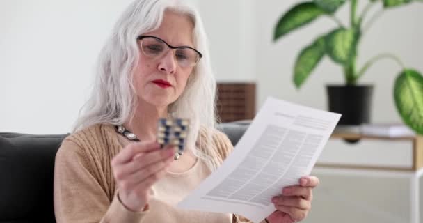 Iäkäs nainen laseissa lukemassa ohjeita huumeiden 4k elokuva hidastettuna. Huumeiden sivuvaikutukset iäkkäillä ihmisillä käsite - Materiaali, video