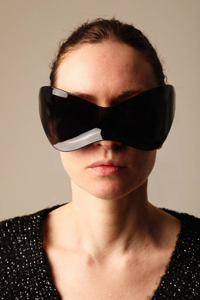 Vertical portrait of confident young woman wearing sunglasses posing indoor. High quality photo. - Fotó, kép