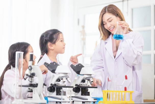 Класс начальной науки, Веселая девочка с учителем-ученым в школьной лаборатории, Научный лаборатор - Фото, изображение