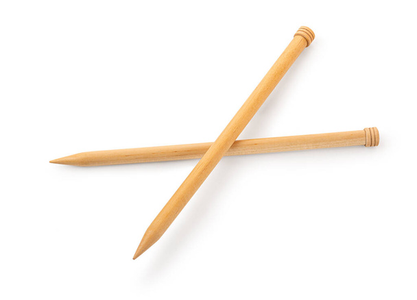 Un par de agujas de tejer de madera grandes desde una perspectiva baja aisladas contra un fondo blanco. - Foto, imagen