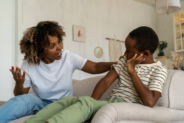 A fiatal, irritált afro-amerikai anya próbálja megtanítani a rossz gyereknek, mi a fegyelem. Feldúlt, hogy anya leszidta a fiát. Szülői felügyelet, szülő-gyermek konfliktus fogalma - Fotó, kép