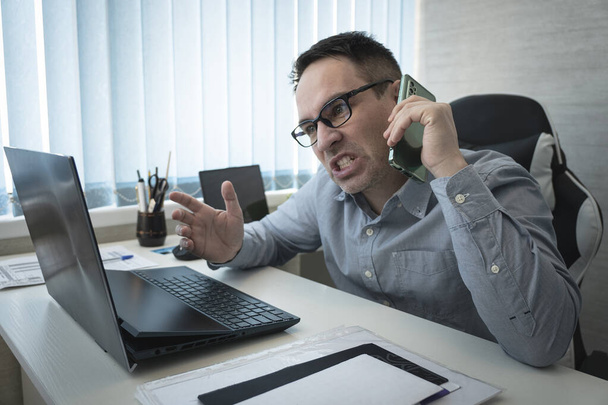 Angry businessman talking on the phone in office. aggression and stress of the boss. Emotional business communication over the phone. the evil boss is not happy with the job. - Foto, Bild