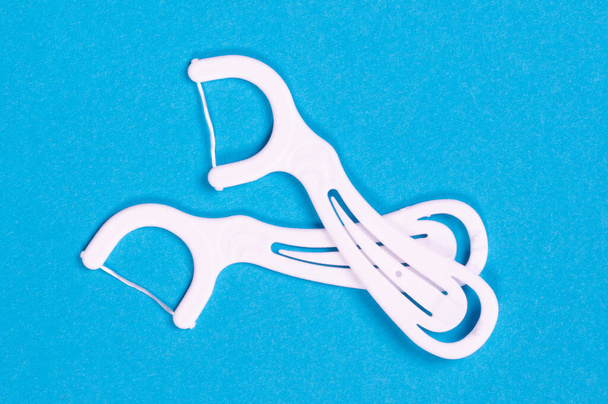Λευκές οδοντογλυφίδες με νήμα απομονωμένο με μονοπάτι απόληξης πάνω από μπλε φόντο - Φωτογραφία, εικόνα