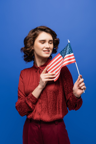 profesor de idiomas positivo sonriendo mientras mira la bandera de EE.UU. aislada en azul - Foto, Imagen