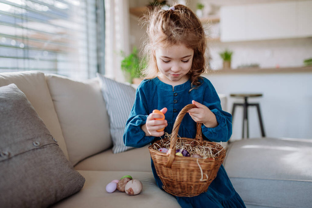 Portrait of little girl holding basket with the easter eggs. - Фото, изображение