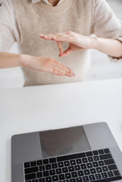 Ausgeschnittene Ansicht des Lehrers zeigt Gebärdensprache-Geste während Online-Unterricht auf Laptop  - Foto, Bild