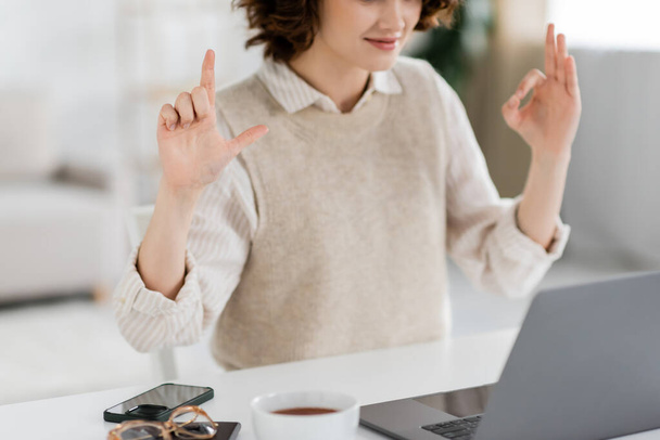 обрізаний вид викладача мови жестів, що показує знаки алфавіту під час онлайн уроку на ноутбуці вдома
 - Фото, зображення