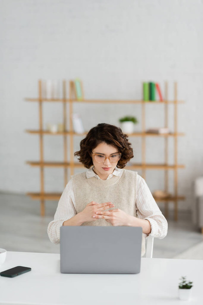 Gözlüklü genç bir kadın evdeki dizüstü bilgisayarda çevrimiçi ders sırasında işaret diliyle kelime gösteriyor. - Fotoğraf, Görsel