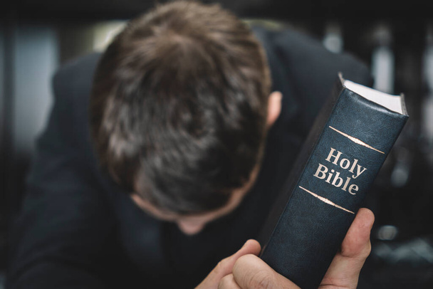 prayer man hand on Bible on dark room. bible in hand - Photo, Image