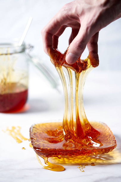 Thick golden syrup or caramel or honey dripping from the spoon into the plate. White background. High quality photo - Фото, зображення