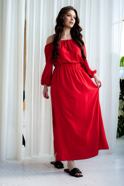 Beautiful smiling woman in long red dress sensual posing - Fotó, kép
