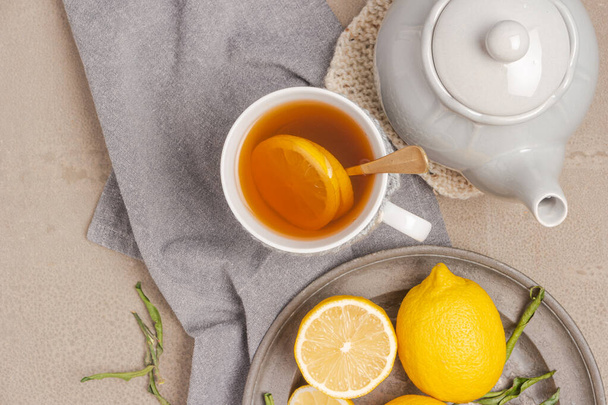 Cup of tea and lemon. A cup of tea with lemon, mint, ginger and honey on on grey table. Flat lay. Top view - Photo, image