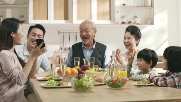 boldog három generációs ázsiai család élvezi az együtt töltött időt, miközben otthon étkeznek - Felvétel, videó