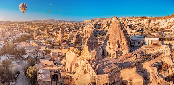 Escénica vista panorámica aérea de vuelo suave y flotante globos de aire caliente entre casas talladas y hoteles en Capadocia maravilla turca - Foto, imagen