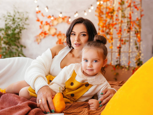 Mom and two little beautiful daughters in autumn with pumpkins and yellow leaves. Family cozy autumn day concept. High quality photo - Fotografie, Obrázek