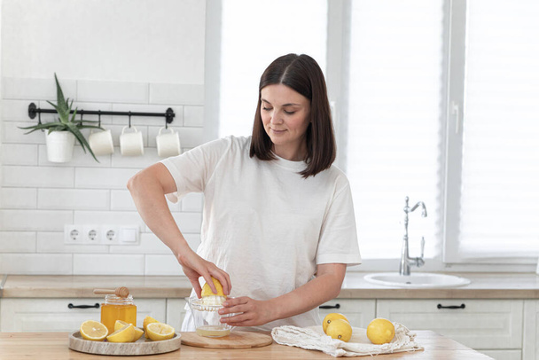 木の板でレモンを切る若い女性。新鮮なレモネードの準備。ラベンダーとレモン - 写真・画像