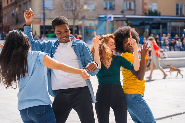 Multi ethnic young friends dancing in a city square, authentic group of diverse friends having fun - Photo, image