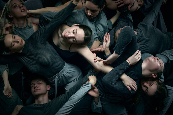 Close-up image of young people making impressive dance performance against black studio background. Crowd. Concept of modern freestyle dance, contemporary art, movements, hobby and creative lifestyle - Zdjęcie, obraz