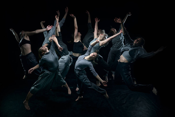 Top view. Expressive contemp dance. Group of young people dancing against black studio background. Concept of modern freestyle dance, contemporary art, movements, hobby and creative lifestyle - Photo, image