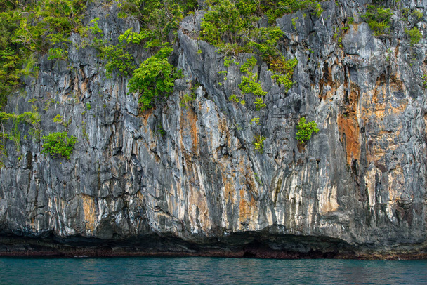 Dieses Foto zeigt die atemberaubend zerklüftete Küste der Philippinen. Eine Reihe felsiger Felsvorsprünge, die von den Wellen glatt getragen werden, erstrecken sich bis zum Horizont, während das türkisfarbene Meer um sie herum wirbelt.. - Foto, Bild