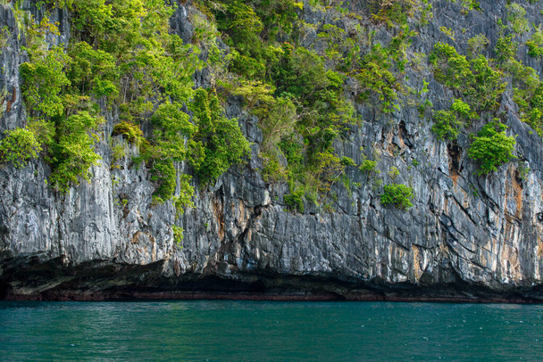 Dieses Foto zeigt die atemberaubend zerklüftete Küste der Philippinen. Eine Reihe felsiger Felsvorsprünge, die von den Wellen glatt getragen werden, erstrecken sich bis zum Horizont, während das türkisfarbene Meer um sie herum wirbelt.. - Foto, Bild
