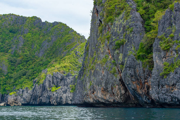 この写真は、フィリピンの驚くほど険しい海岸線を示しています。一連の岩の切り株は、波の重なりによって滑らかに身に着けられ、水平線に伸び、一方、ターコイズブルーの海はそれらの周りを旋回します。. - 写真・画像