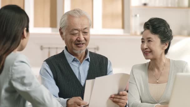 senior aziatisch paar blij met de voorwaarden van een contract gepresenteerd door een verkoopster - Video