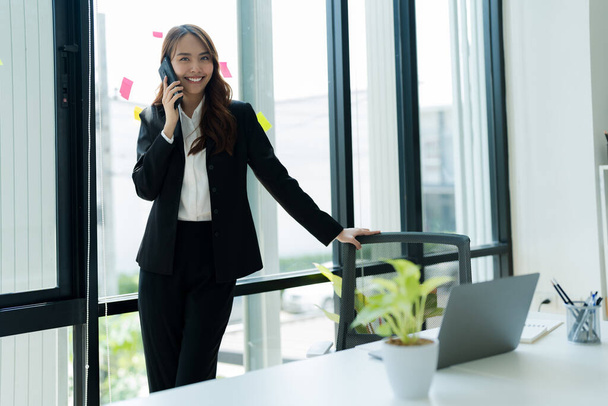 Glücklich junge asiatische Geschäftsfrau trägt Anzug mit Handy. - Foto, Bild