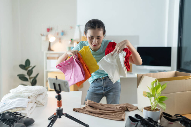 Gyönyörű fiatal nő dolgozik az online áruház visel alkalmi ruhák, ő ellenőrzi az ügyfél laptop címét és termékinformáció Saját kisvállalkozás. - Fotó, kép