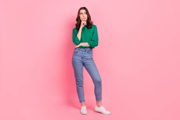 Full size photo of ponder pensive thoughtful girl dressed jeans green shirt look empty space finger on chin isolated on pink background. - Фото, зображення