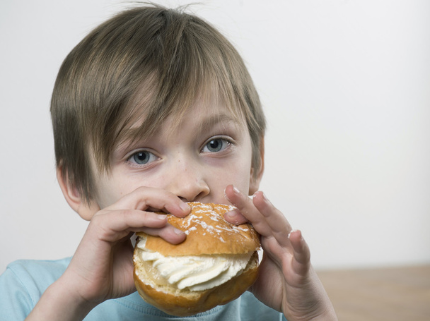 Kremalı çörek yiyen genç çocuk - Fotoğraf, Görsel